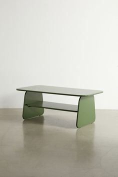 a green coffee table sitting on top of a cement floor next to a white wall