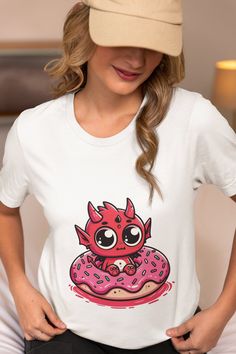 Embrace the playful side of fashion with our "Adorable Demon Donut Lover Tee"! This charming unisex T-shirt features an eye-catching print of a cute demon cuddling with a delicious donut, offering a unique twist to your everyday style. The soft, high-quality fabric ensures all-day comfort, making it perfect for anyone who loves to add a touch of whimsy to their wardrobe. Ideal for casual outings, this graphic tee is sure to start conversations and bring smiles. Whether you're treating yourself o Kawaii T-shirt With Cartoon Print Crew Neck, Cute Cartoon Print Crew Neck T-shirt, Cute Crew Neck T-shirt With Cartoon Print, Kawaii T-shirt With Funny Print And Crew Neck, Kawaii Cotton T-shirt With Crew Neck, Kawaii Funny Print Crew Neck T-shirt, Playful Cartoon Print Crew Neck T-shirt, Playful Crew Neck T-shirt With Cartoon Print, Kawaii Cotton Crew Neck T-shirt