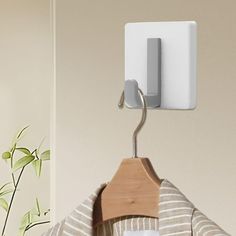 a white coat hanger on a wall next to a brown and white striped shirt