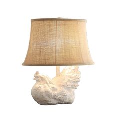 a white chicken lamp sitting on top of a table next to a beige shade light