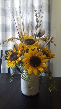 a vase filled with sunflowers on top of a wooden table