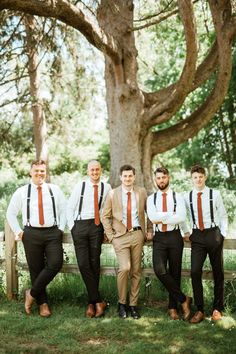 a group of men standing next to each other in front of a tree