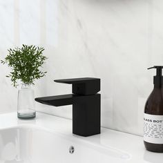 a black faucet sitting on top of a bathroom sink next to a bottle of soap