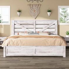 a white bed sitting in a bedroom on top of a hard wood floor next to two windows