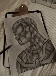 a drawing of a spider man on top of a sheet of paper next to a pen