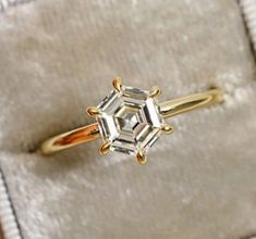 an engagement ring with three stones in it sitting on a white velvet box, close up