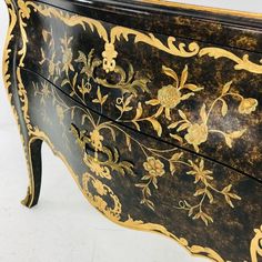 an ornate black and gold painted dresser with flowers on the front, side panels and drawers