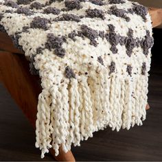 a crocheted blanket sitting on top of a wooden bench