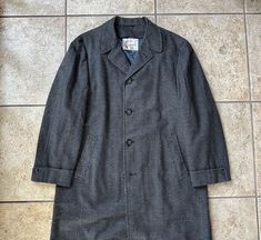 "Here is a vintage sack overcoat by \"Rexvelo\" for \"Shillito's\" of Cincinatti, OH, that can be dated to the 1950s. There is no size tag, but it could fit sizes 40 through 42 Regular, depending on preferred overcoat fit; still, please use the measurements provided as a reference.  Union-made in the USA of what is assuredly 100% tweed wool, it has a houndstooth check of gray & charcoal along with a red windowpane plaid. The quality is beyond superb with full canvassing, piping on the inner seam Vintage Wool Long Coat, Vintage Long Coat For Workwear, Vintage Houndstooth Outerwear With Notch Lapel, Fitted Vintage Outerwear With Houndstooth Pattern, Retro Tweed Outerwear For Business, Vintage Tailored Winter Outerwear, Vintage Single-breasted Tweed Outerwear, Tailored Vintage Winter Outerwear, Tailored Vintage Outerwear For Winter