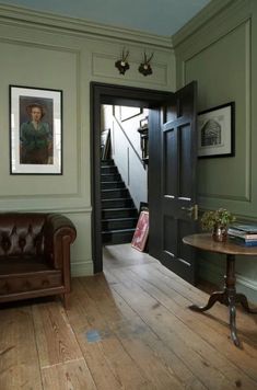 an open door leading to a living room with wooden flooring and walls painted green