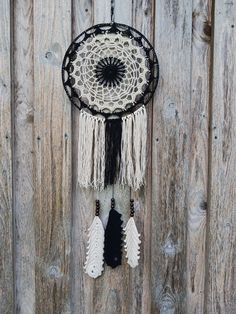 a black and white dream catcher hanging on a wooden fence