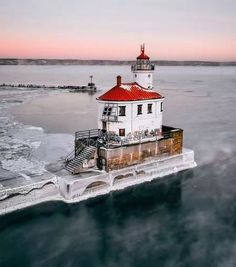 an aerial view of a lighthouse in the middle of the ocean with ice around it