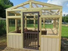 a small wooden greenhouse in the middle of a yard