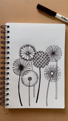 a drawing of dandelions on a notepad next to a pen