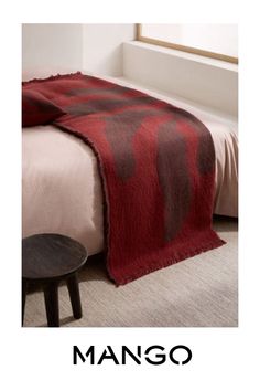 a bed with a red and brown blanket on top of it