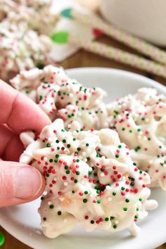 someone is picking up some white and green sprinkles from a plate on the table