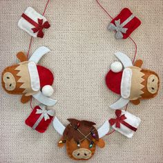 a group of stuffed animals hanging from strings on a white wall with red and white christmas decorations