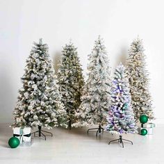 three christmas trees with presents in front of them on a white floor and one is green