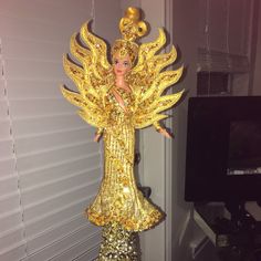 a gold and black doll is standing on a table