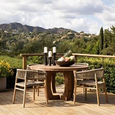 a wooden table with two chairs and a bowl of fruit on it sitting on a deck