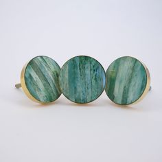 three green and gold cufflinks sitting on top of each other in front of a white background