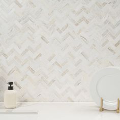 a white plate and soap dispenser sitting on a counter top next to a marble wall