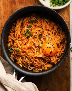 an egg is sitting on top of noodles in a skillet next to some vegetables