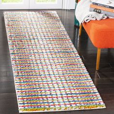 a colorful rug is on the floor next to an orange chair and bookshelf