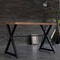 a wooden table sitting in front of a brick wall next to a potted plant