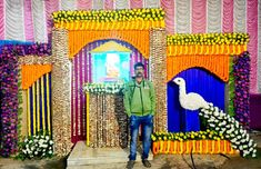 a man standing in front of a stage decorated with flowers and peacocks on it