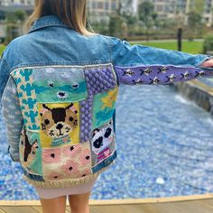 a woman with her back to the camera wearing a jean jacket that has cats on it