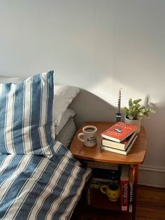 a bed with blue and white striped sheets on it next to a table with two books