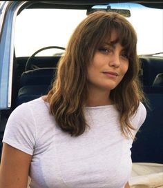 a woman standing in front of a truck with her hand on her hip and looking off to the side