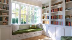 there is a window seat in the room with many bookshelves on both sides