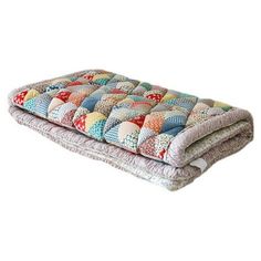 a multicolored patchwork quilted pillow on a white background