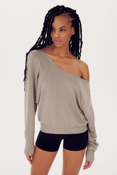 A young woman with braided hair, wearing a beige SPLITS59 Indy Dolman Fleece Sweatshirt - Latte and black shorts, posing against a white background. Comfy French Terry Tops For Fall, Oversized Raglan Sleeve Sweatshirt For Loungewear, Casual Fall Workout Sweats, Sporty Raglan Sleeve Sweats For Fall, Fall Loungewear Sweats With Raglan Sleeves, Fall Raglan Sleeve Sweatshirt For Loungewear, Sporty Relaxed Fit Sweats For Relaxation, Cozy Fit Tops With Soft Texture For Loungewear, Soft-washed Sweats For Fall