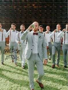 a group of men in suits and bow ties are walking through the grass with beer