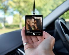 a person holding up an mp3 player to take a picture in the car with their cell phone