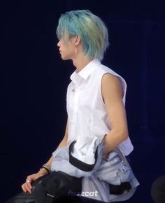 a woman with blue hair is carrying a bag on her back while walking down the runway