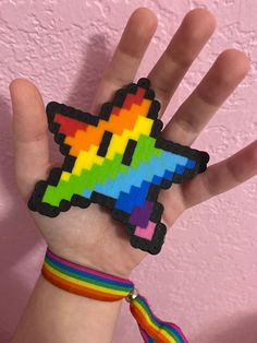 a person's hand with a rainbow colored pixelated object on it