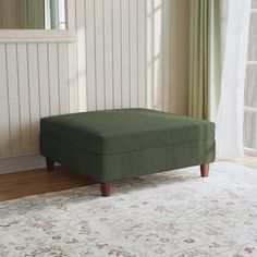 a green footstool sitting on top of a rug in front of a window