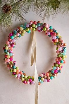 an ornament made out of beads on a white surface next to a pine tree