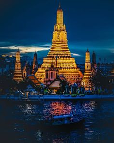 a boat floating on top of a body of water next to a tall building at night