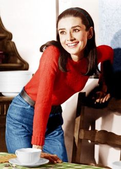 a woman in a red sweater leaning over a table with a coffee cup on it