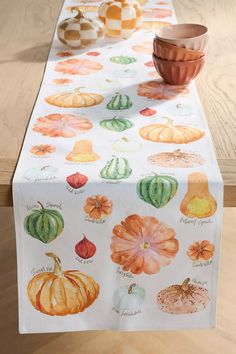 a table topped with a white table cloth covered in lots of different types of pumpkins