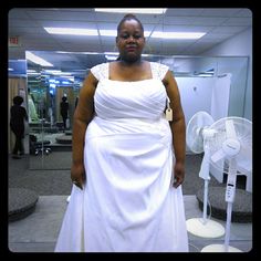 a woman in a white dress standing next to a fan