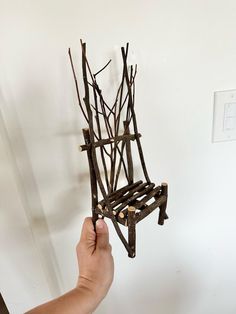 a hand holding a piece of art made out of branches