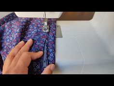 a woman is using a sewing machine to sew on a blue and red fabric