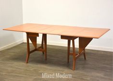 a wooden table sitting on top of a hard wood floor next to a white wall