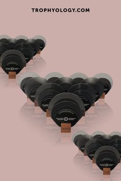 a bunch of black discs sitting on top of each other in front of a pink background